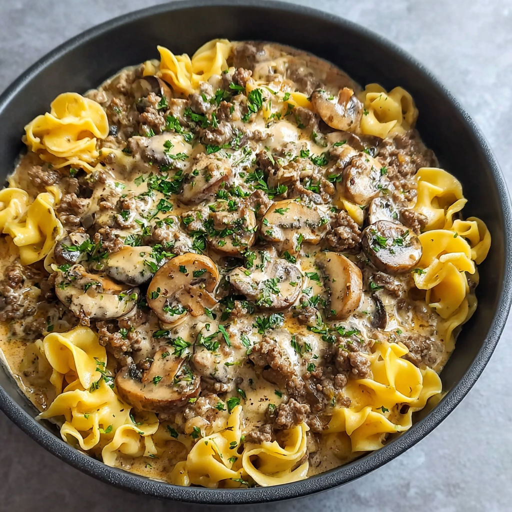 A bowl of pasta with mushrooms and meat.