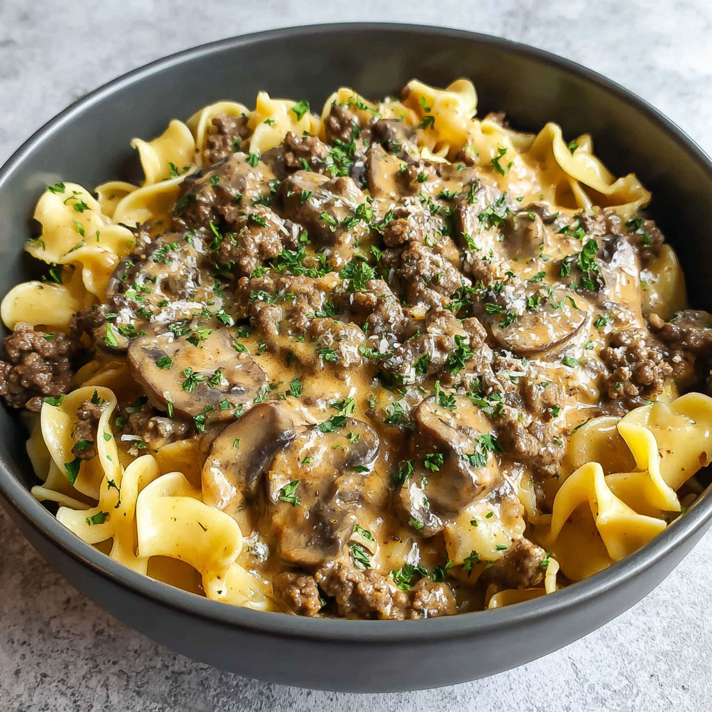 A bowl of pasta with mushrooms and meat.