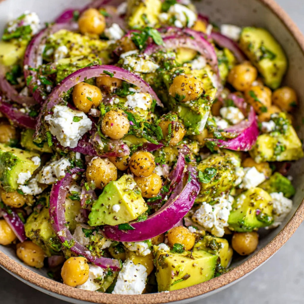 A bowl of food with onions, avocado, and feta cheese.