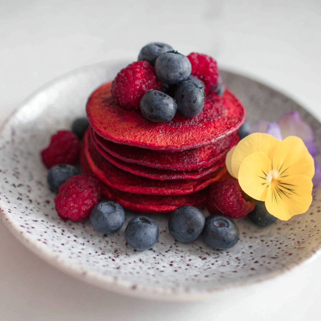 A plate of food with berries and a flower.