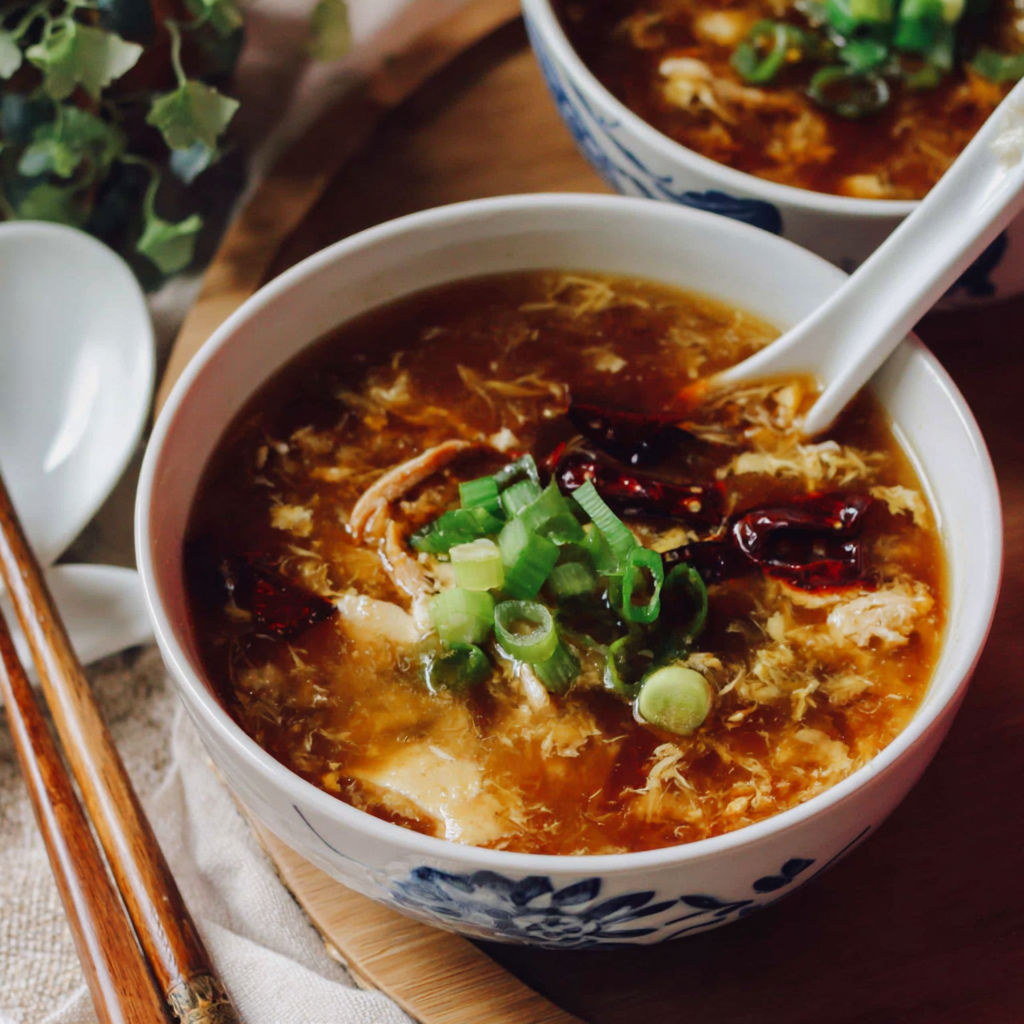 A bowl of soup with chopsticks and a spoon.