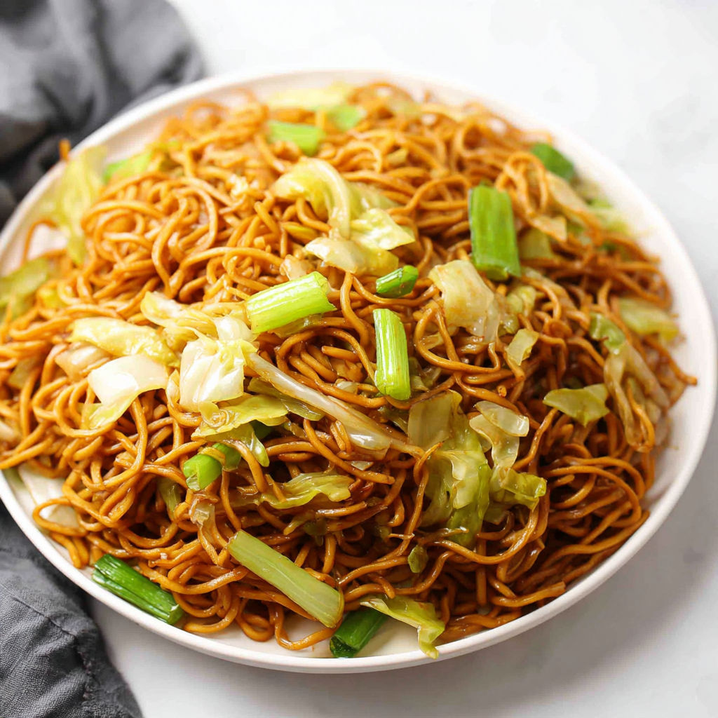 A plate of chow mein noodles with vegetables.