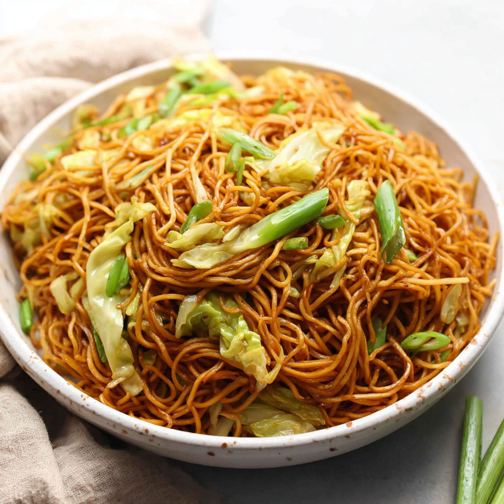 A bowl of chow mein noodles with vegetables.