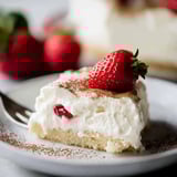 A slice of vegan tres leches cake with strawberries on top.