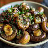 A bowl of mushrooms with herbs and spices.