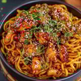 A bowl of noodles with chicken and vegetables.