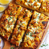 A wooden cutting board with slices of tandoori chicken garlic bread.