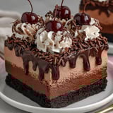 A chocolate mousse brownies dessert with cherries on top.