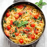 A pan of pasta with tomatoes and basil.