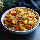 A bowl of rice with vegetables and pineapple.