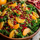 A bowl of salad with oranges, pomegranates, kale, and a honey-lemon vinaigrette.