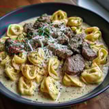A bowl of food with meat and pasta.