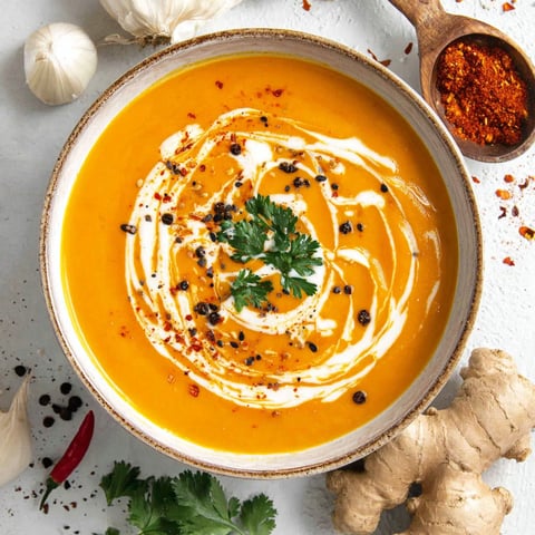 A bowl of sweet potato soup with a spoon in it.