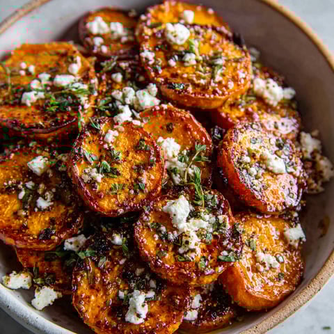 A bowl of roasted sweet potatoes with feta cheese and honey.