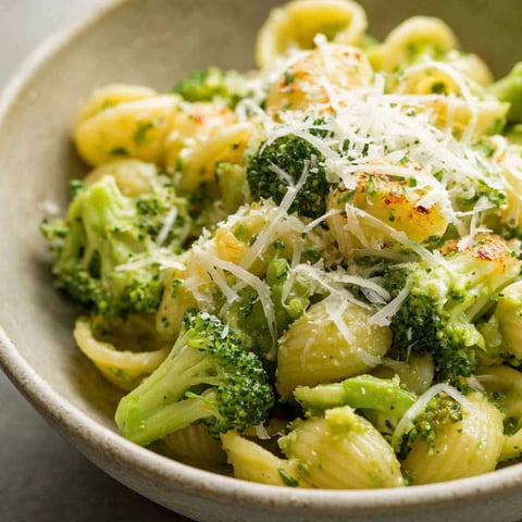 A bowl of pasta with broccoli and cheese.